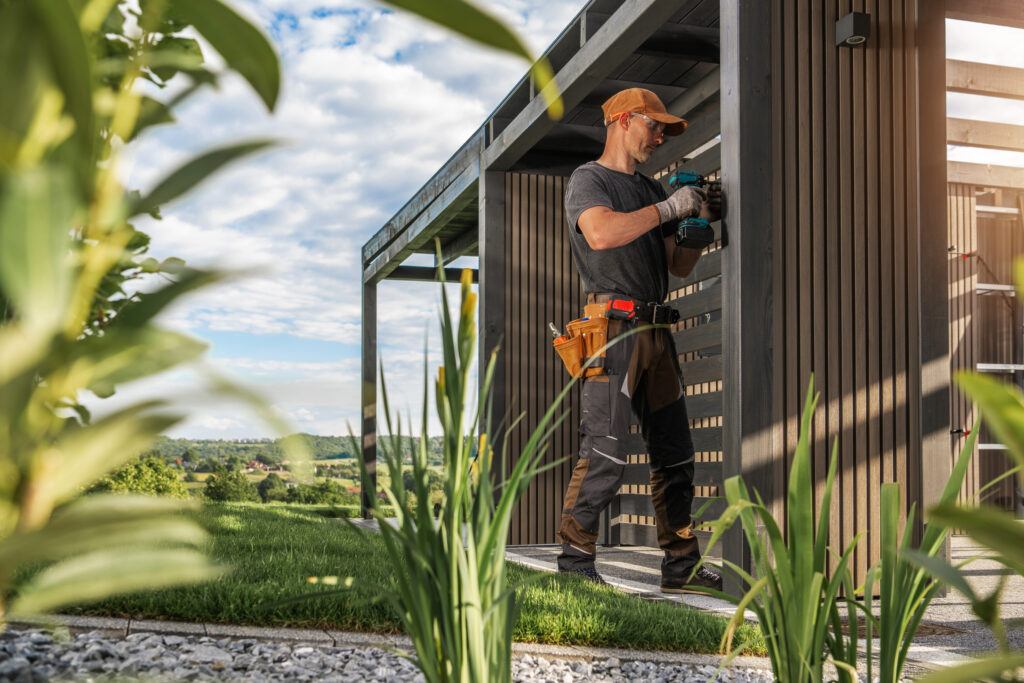 Construction Worker Installing Features on Modern Outdoor Structure in a Landscaped Garden During Sunny Day